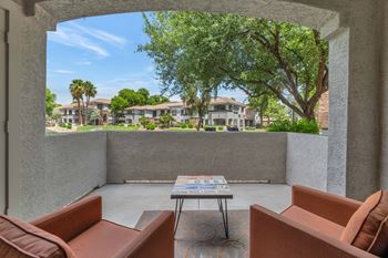 A patio with couches and a table in front of a window