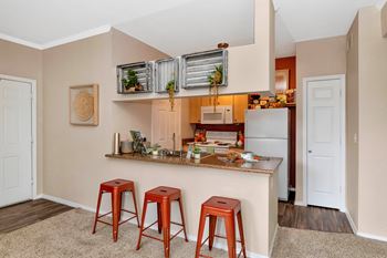 A kitchen with a bar and three stools