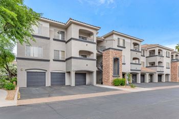 A street view of an apartment building with garage doors