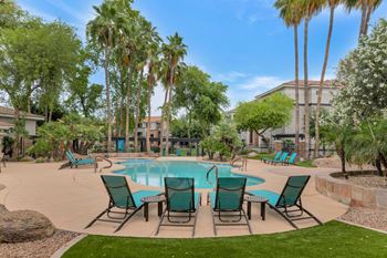 A swimming pool with patio furniture and palm trees