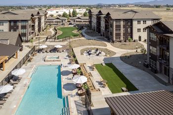 A large swimming pool surrounded by a grassy area and apartment buildings