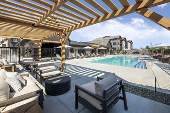 A wooden pergola over a poolside seating area
