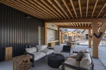 A modern outdoor living space with a wooden ceiling and black wall