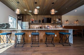 Four blue bar stools are in front of a bar