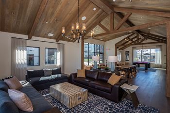A large, open-concept living room with wooden beams and a variety of seating options