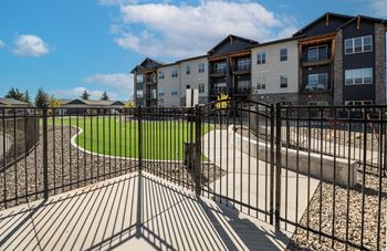 A black metal fence surrounds a playground area in front of apartment buildings