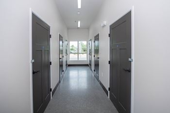 A long hallway with doors on both sides and windows in the distance