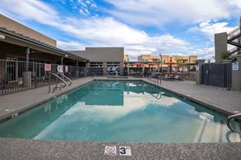 A swimming pool at a hotel with a blue cloudy sky