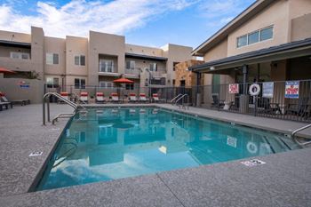 A swimming pool with chairs in front of a building