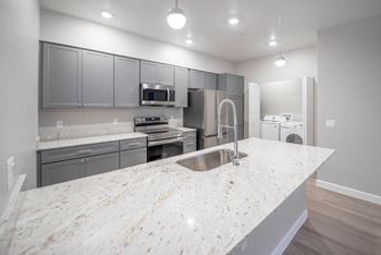 A kitchen with a marble counter top and a sink