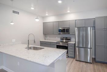A kitchen with stainless steel appliances and a marble counter top