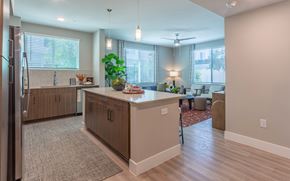 Phoenix apartment for rent - A kitchen with a refrigerator on the left and a dining area with a table and chairs.