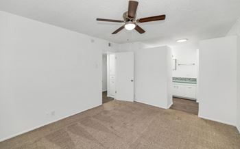 A room with a ceiling fan and carpeted floor.
