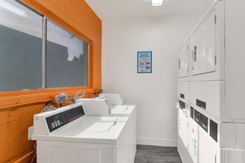 A clean, white-walled room with a row of white cabinets and a microwave on a counter.