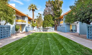 A row of houses with blue fences and green lawns.