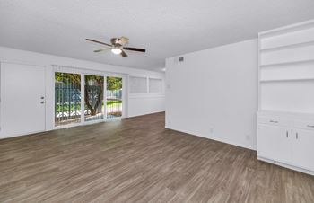 A room with a ceiling fan and wooden flooring.