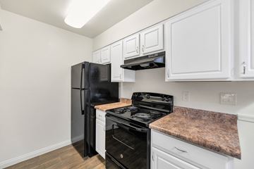 Phoenix apartment for rent - A black fridge and stove in a kitchen with white cabinets.