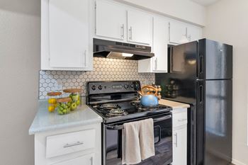 A kitchen with black appliances and white cabinets