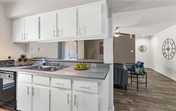 An open kitchen and living room with white cabinets and a sink