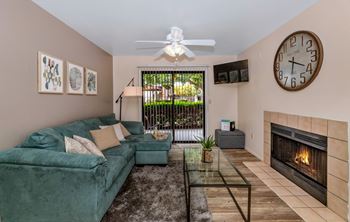 A living room with a green couch, a fireplace, and a ceiling fan.