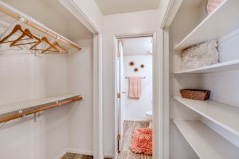 A white closet with a doorway leading to a bathroom.