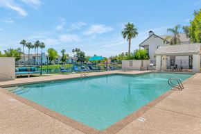 Chandler apartment for rent - a swimming pool with a house and palm trees in the background