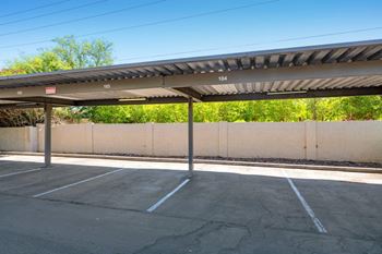 A parking lot with a concrete wall and a metal roof.