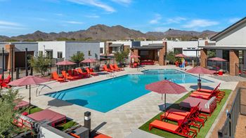 A swimming pool with red chairs and umbrellas at a resort