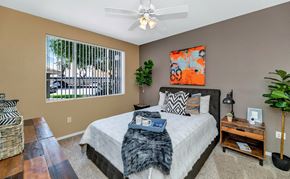 Chandler apartment for rent - A bedroom with a large bed, a ceiling fan, and a window with blinds at Montage at Pecos Ranch Apartments, Arizona