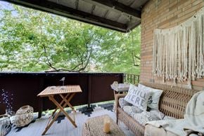 Racine apartment for rent - A balcony with a couch, table, and a view of trees.