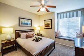 Dallas apartment for rent - A bedroom with a bed, nightstand, and window seat.