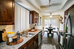 Tucson apartment for rent - kitchen with stainless steel appliances and granite counter tops and a dining room with a table
