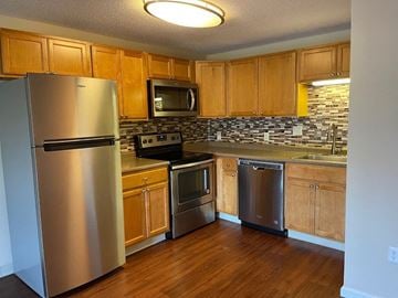 Chelmsford apartment for rent - A kitchen with wooden cabinets and a stainless steel refrigerator.