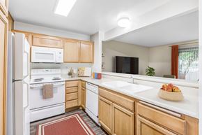 Goleta apartment for rent - Goleta, CA, Apartments Near Trader Joe's - Encina Meadows - Kitchen With Light Wood Cabinets, White Stove And Microwave, Double Sink And Dishwasher.