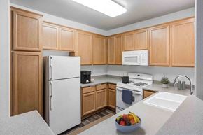 Santa Barbara apartment for rent - Apartments for Rent in Goleta CA - Sumida Gardens - Kitchen with Wood-Style Floor, Area Rug, White Appliances, Wood Cabinetry, Grey Countertops, Overhead Lighting, and Breakfast Bar Area