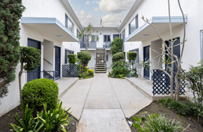 Los Angeles apartment for rent - A white building with a blue door and a small garden in front.