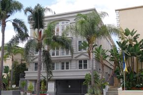 Los Angeles apartment for rent - A grey building with a black gate and a flag on the right side.