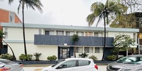 Los Angeles apartment for rent - a building with a black roof and palm trees in front of it