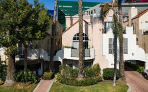 West Hollywood apartment for rent - A white building with a balcony is surrounded by greenery.