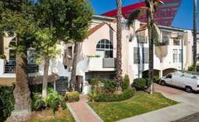 West Hollywood apartment for rent - A white building with a red roof and a palm tree in front.