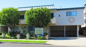 Los Angeles apartment for rent - a white building with a sign and trees in front of it