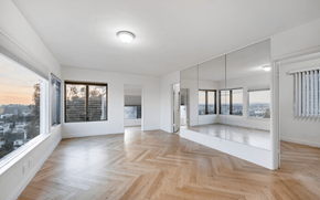 Los Angeles apartment for rent - A spacious room with wooden flooring and large windows overlooking a cityscape.