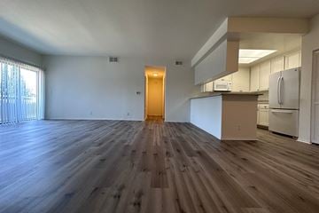 Los Angeles apartment for rent - A room with wooden flooring and a kitchen area in the background.