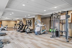Bloomington apartment for rent - a gym with cardio machines and weights on a wooden floor