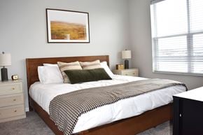 Inver Grove Heights townhouse for rent - A bedroom with a bed, nightstand, and lamp.