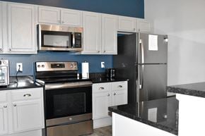Woodbury townhouse for rent - A kitchen with white cabinets and a black counter.