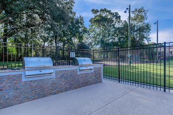 A patio with two bbq pits and a black fence
