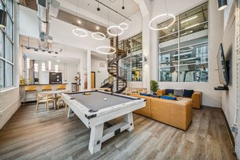 A room with a pool table and a spiral staircase