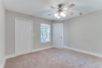 An empty living room with a ceiling fan and a window