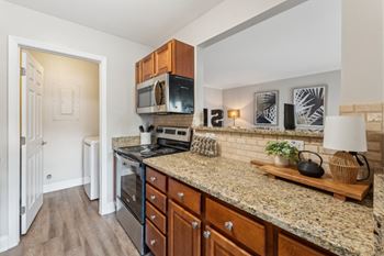 A kitchen with granite countertops and wooden cabinets.